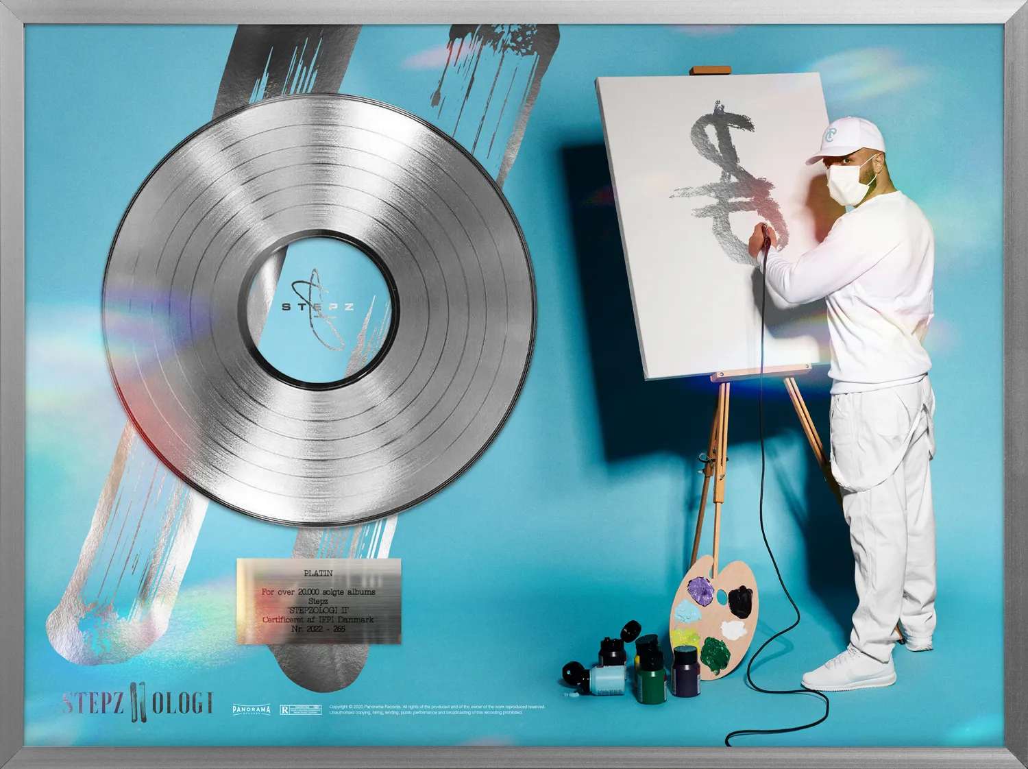 Platinplade for Stepz&rsquo; album Stepzologi II med kunstneren foran l&aelig;rred og staffeli i bl&aring;t studie. Design og art direction af Comugraph.