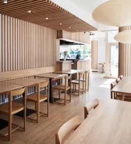 Lyst og moderne restaurantinteri&oslash;r hos Izumi med tr&aelig;paneler, minimalistiske m&oslash;bler og naturligt lys.