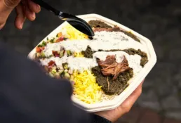 Takeaway bowl fra KUKU Iranian Kitchen med safranris, mørt kød og frisk salat.