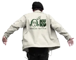 Person if&oslash;rt beige jakke med KUKU Iranian Kitchen logo trykt p&aring; ryggen.