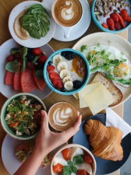 Brunchbord hos Social Brew med kaffe, croissant, frugt, avocado, bowls og friske råvarer, vist i farverigt og elegant layout.